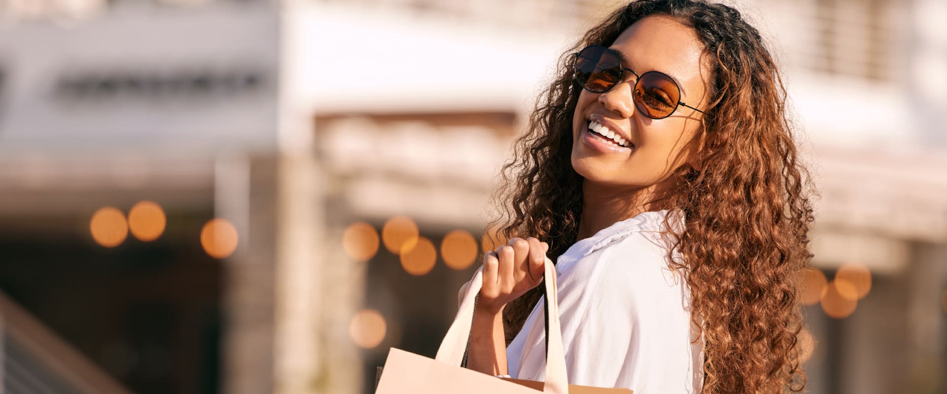 Smiling woman shopping outdoors at Citrus Town Center in Citrus Heights, holding bags in warm sunlight